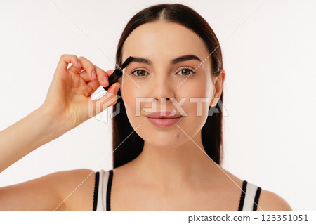 Young Woman Applying Brow Mascara for a Stylish Makeup Look 123351051