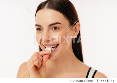 Smiling Individual Enjoying a Piece of Wellness Supplement Smiling Individual Enjoying a Piece of Wellness Supplement 123351074