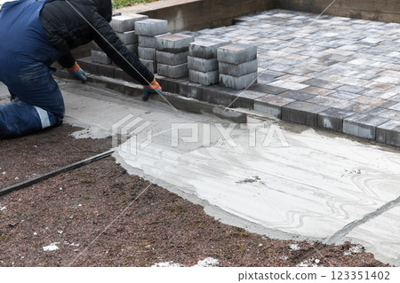 Professional Paver Installing Concrete Bricks for an Outdoor Pathway 123351402