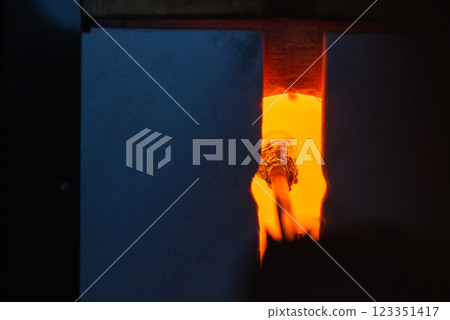 An open furnace with molten glass on a blowpipe inside. Glass blowing An open furnace with molten glass on a blowpipe inside. Glass blowing 123351417