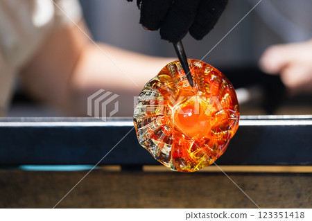 Molding molten glass into a flower shape. Works of a glass blowing Molding molten glass into a flower shape. Works of a glass blowing 123351418