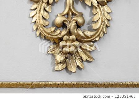 Gold Ornamental Design Element Featuring Decorative Floral Motif on White Wall 123351465
