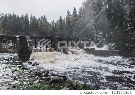 Serene winter landscape featuring a rustic dam streaming water 123351561