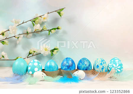 Happy Easter concept. Abstract Easter composition with blue decorated eggs, feathers, flowering branches and flowers. Banner for screen with space for greeting text Happy Easter concept. Abstract Easter composition with blue decorated eggs, feathers, flowering branches and flowers. Banner for screen with space for greeting text 123352866