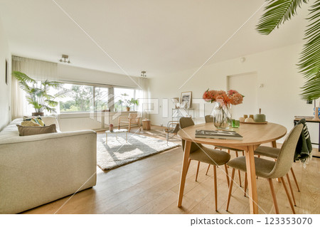A spacious and stylish living area featuring a light-colored sofa, natural light, and decorative plants, creating a warm, inviting atmosphere. 123353070