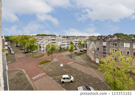 A picturesque view capturing a quiet urban street, lined with trees and residential buildings, showcasing a peaceful atmosphere. A picturesque view capturing a quiet urban street, lined with trees and residential buildings, showcasing a peaceful atmosphere. 123353181