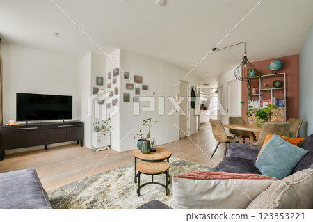 A stylish and contemporary living room featuring elegant furniture, a cozy seating area, and vibrant wall decorations, perfect for relaxing or entertaining guests. 123353221