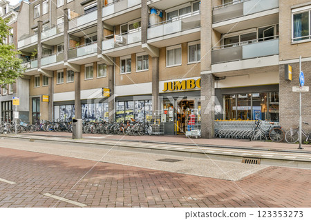 A vibrant shopping area featuring a grocery store named Jumbo, surrounded by parked bicycles and modern apartment buildings. 123353273