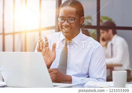 a man at a workplace at a table in front of a computer greeting colleagues via video communication a man at a workplace at a table in front of a computer greeting colleagues via video communication 123353309