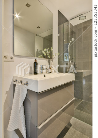 A sleek and contemporary bathroom featuring a stylish sink, mirror, shower, and tasteful decor elements creating a serene ambiance. 123353343