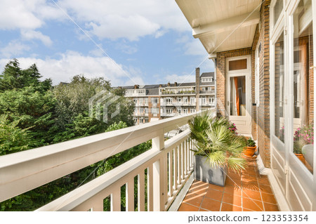 A stylish balcony featuring lush plants and a scenic view of city buildings under a bright blue sky, creating a peaceful urban retreat. 123353354