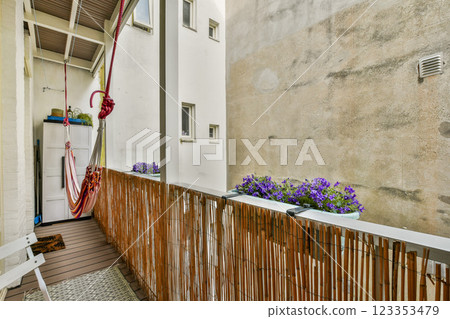 A charming balcony view featuring a relaxing hammock, decorative plants, and a minimalist design, perfect for enjoying serene moments outdoors in an urban environment. 123353479