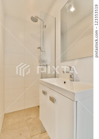 A sleek modern bathroom featuring a minimalist design with white tiles, a stylish sink, and a shower. Ideal for contemporary home aesthetics. 123353519