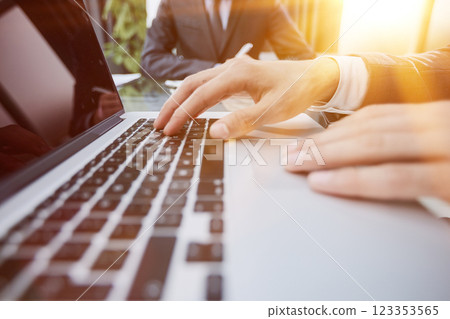 Men's hands are typing on a laptop keyboard against the background of colleagues. side view 123353565
