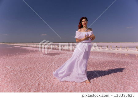 Woman White Dress Pink Salt Lake - A woman in a white dress stands on a pink salt lake with the blue sky in the background. Woman White Dress Pink Salt Lake - A woman in a white dress stands on a pink salt lake with the blue sky in the background. 123353623