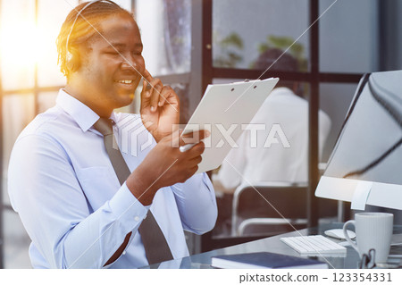 a man at a computer in a call center talking using headphones with a microphone 123354331