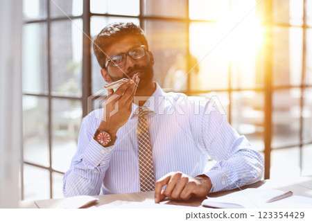 Confident businessman sitting and talking on the phone at office 123354429