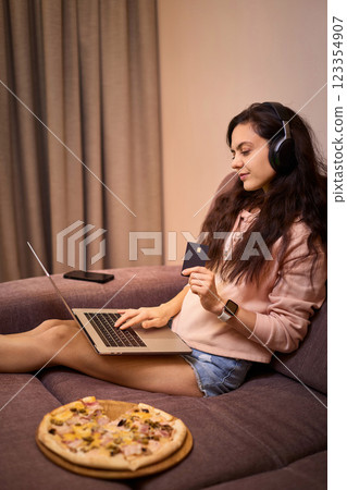 Caucasian woman using laptop holding black credit card, online shopping concept Caucasian woman using laptop holding black credit card, online shopping concept 123354907