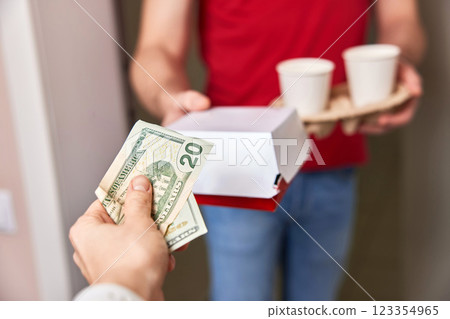 delivery man giving food box and paper coffee cups to customer and taking payment delivery man giving food box and paper coffee cups to customer and taking payment 123354965