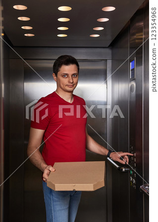 Deliveryman holding pizza box in elevator, food delivery to your home. Deliveryman holding pizza box in elevator, food delivery to your home. 123354968