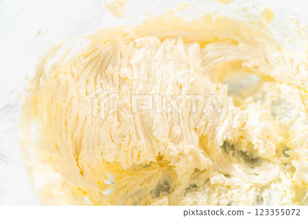 In a large mixing bowl, the ingredients are expertly mixed to create a delectable cream cheese buttercream for the Carrot Bundt Cake. 123355072