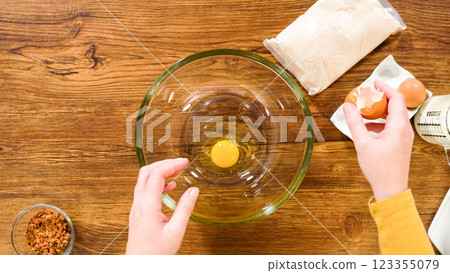 Flat lay. In a glass mixing bowl, a large hand whisk expertly blends the ingredients for a delectable gingerbread bundt cake with caramel frosting. 123355079