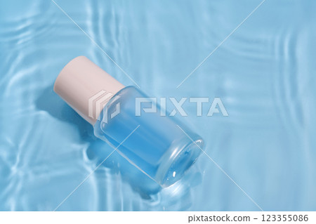 Bottle with moisturizing serum in water on blue background. 123355086