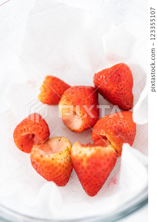 Freshly washed and dried strawberries are carefully arranged in a glass bowl lined with paper towel, ready for snacking or further use. 123355107