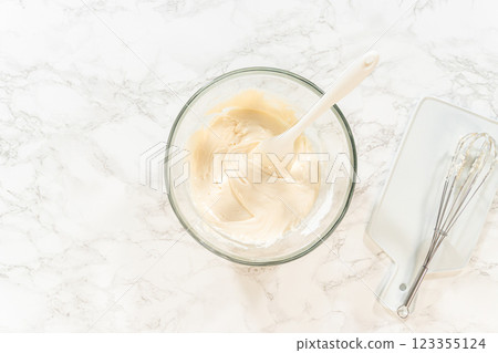 Close-up of Simple White Royal Icing nearly finished, with a smooth and creamy texture in the glass bowl and whisk resting on the side. Close-up of Simple White Royal Icing nearly finished, with a smooth and creamy texture in the glass bowl and whisk resting on the side. 123355124