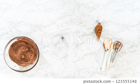 Flat lay. The chocolate icing is carefully transferred into a piping bag, ready to adorn the scrumptious cupcakes. Flat lay. The chocolate icing is carefully transferred into a piping bag, ready to adorn the scrumptious cupcakes. 123355148