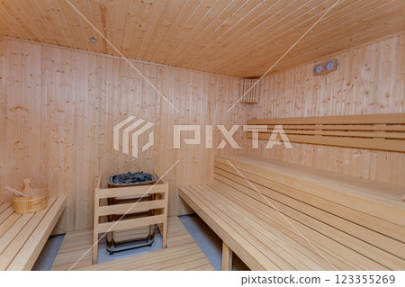 A wooden sauna has traditional benches and a heater, providing a serene space for relaxation A wooden sauna has traditional benches and a heater, providing a serene space for relaxation 123355269