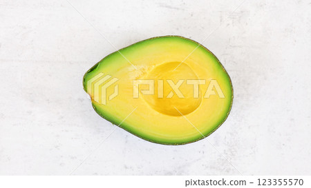 Avocado half, with bright yellow pulp on white stone board, photo from above 123355570