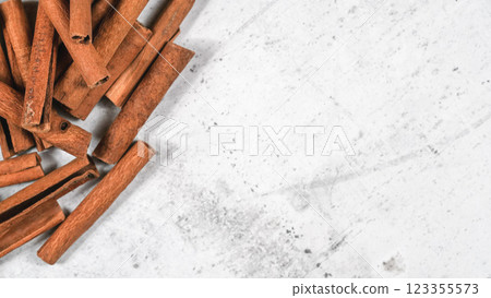 Closeup detail - Heap of cinnamon bark sticks on white stone board, empty space for text right side Closeup detail - Heap of cinnamon bark sticks on white stone board, empty space for text right side 123355573