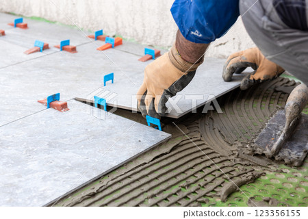 Tiler at work installing new floor with tiles. Construction. Tiler at work installing new floor with tiles. Construction. 123356155