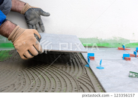Tiler at work installing new floor with tiles. Construction. Tiler at work installing new floor with tiles. Construction. 123356157