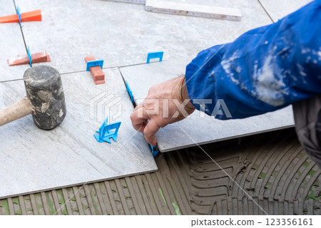 Tiler at work installing new floor with tiles. Construction. 123356161