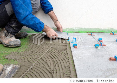 Tiler at work installing new floor with tiles. Construction. Tiler at work installing new floor with tiles. Construction. 123356162