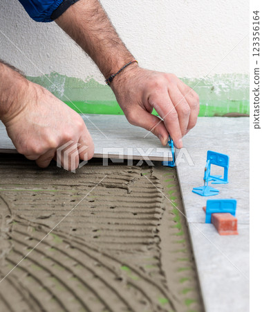 Tiler at work installing new floor with tiles. Construction. 123356164