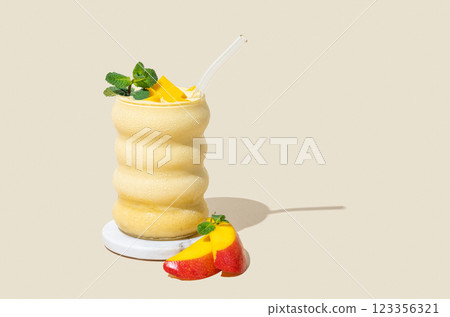 Smoothie with mango and banana in a glass on a yellow background with slice of fruits and shadow. 123356321