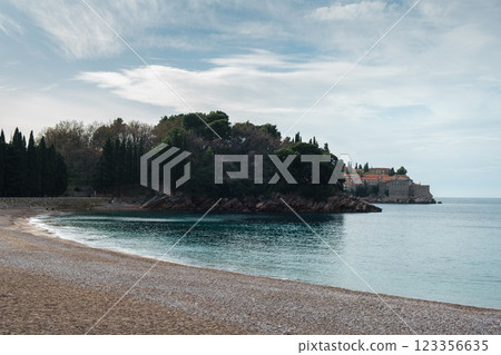 Sveti Stefan island with pebble empty beach with forest and medieval Mediterranean fishing village at sunrise Sveti Stefan island with pebble empty beach with forest and medieval Mediterranean fishing village at sunrise 123356635