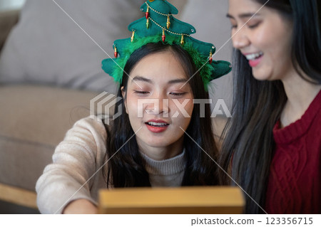 Lesbian Friends Exploring Christmas Gift Surprises with Joyful Anticipation Lesbian Friends Exploring Christmas Gift Surprises with Joyful Anticipation 123356715