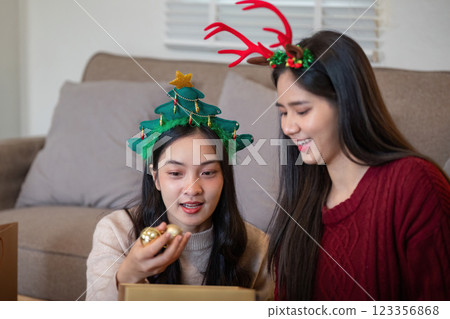 Interracial Lesbian Couple Sharing Magical Christmas Ornaments and Festive Joy Interracial Lesbian Couple Sharing Magical Christmas Ornaments and Festive Joy 123356868
