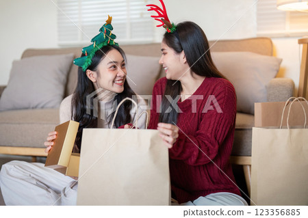 Excited Interracial Lesbian Couple Unwrapping Gifts during Festive Gathering Excited Interracial Lesbian Couple Unwrapping Gifts during Festive Gathering 123356885