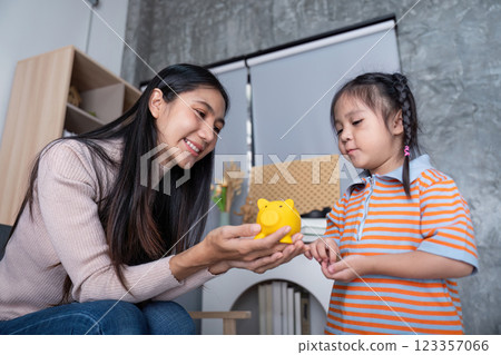 Mother Teaching Daughter Importance of Savings using Piggy Bank Interaction 123357066