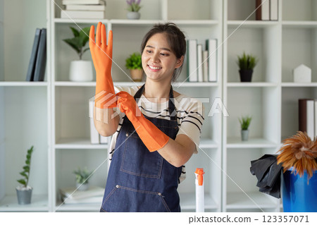 Smiling Housekeeper Putting on Gloves for Safe and Hygienic Cleaning Task 123357071