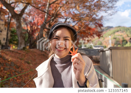 Smiling Asian Woman Enjoying Autumn Holding a Maple Leaf Smiling Asian Woman Enjoying Autumn Holding a Maple Leaf 123357145