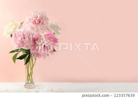 Home interior with decor elements, beautiful spring peony branches in a vase on a light background, abstract flower composition, still life with place for text, flower card for birthday, wedding, 123357639