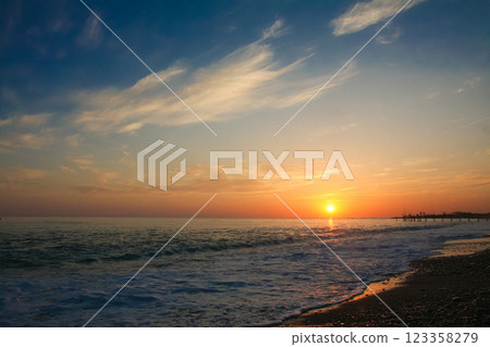 beautiful and colorful sunset, warm light and many clouds, sea waves on the sea coast 123358279