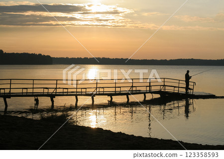 silhouette of a fisherman at sunset on the lake silhouette of a fisherman at sunset on the lake 123358593