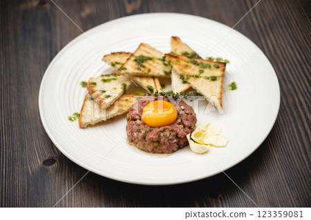 a tasty dish of meat and egg yolk with croutons on a plate. a tasty dish of meat and egg yolk with croutons on a plate. 123359081